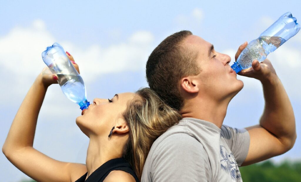 homme et femme en train de boire de l'eau en bouteille.